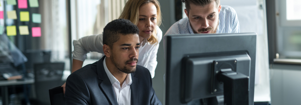 Side view of multiple people working on business computer