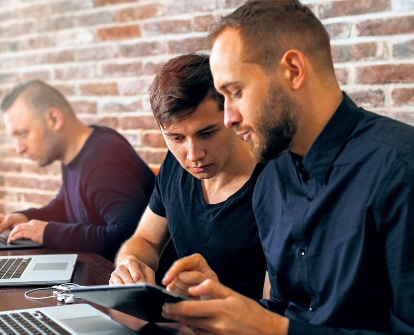 Side view of two IT professionals looking at tablet together