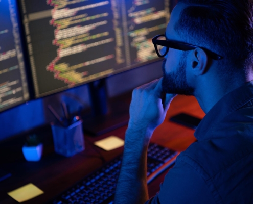 Professional looking at code on computer for vulnerabilities
