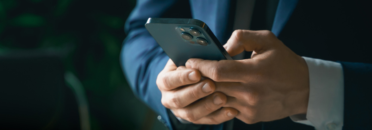 Side view of man in suit typing on smart phone