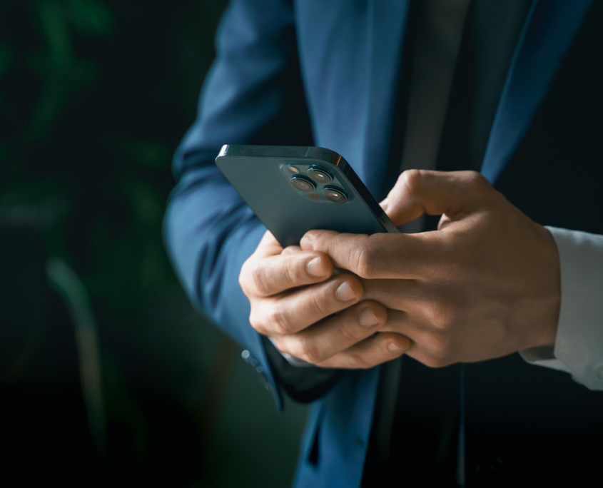 Side view of man in suit typing on smart phone